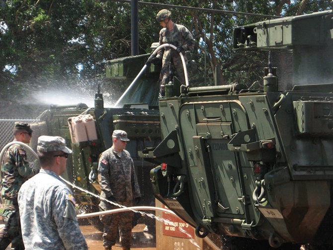 Military personnel washing vehicle